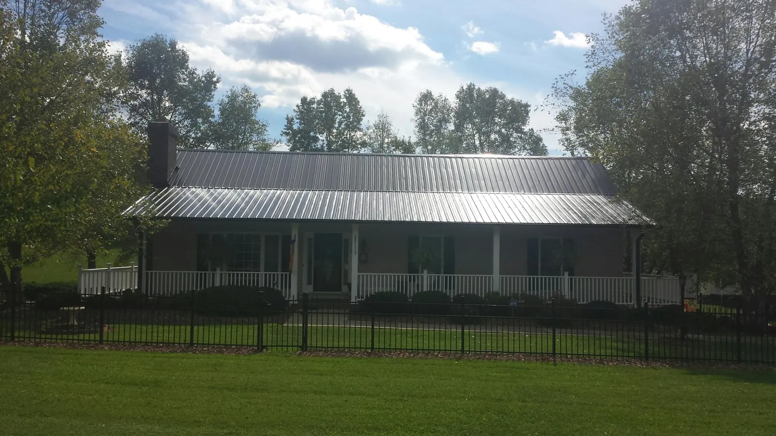 Gray metal roof on a brick ranch with a full width front porch — Gutter Guard Installation work by our crew in Williamson